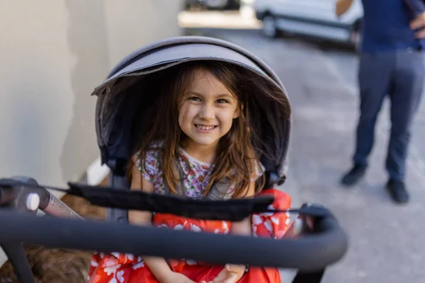 Счастливая маленькая девочка в серой коляске с размытым фоном — стоковое фото