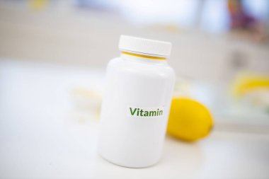 Beyaz masada arka planda limon ve limon bulunan bir şişe vitamin.