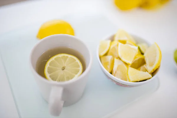 Чашка чая и ломтики лимона на белом столе — стоковое фото
