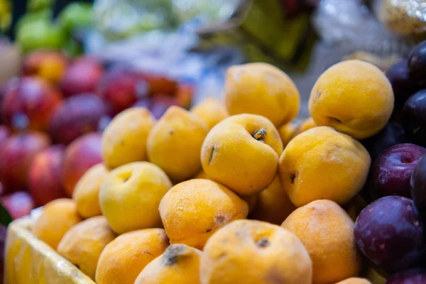 Close-up van kleurrijke fruitkraam met stapels perziken en pruimen — Stockfoto