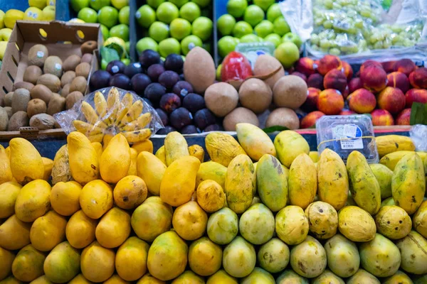 Farverige frugtstativ med mango, ferskner, mamey, grønne æbler og meget mere - Stock-foto