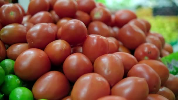 Pile of tomatoes on stand with more vegetables as background — Stock Video