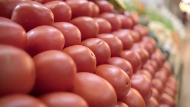 Pile of tomatoes on stand with more vegetables as background — Stock Video