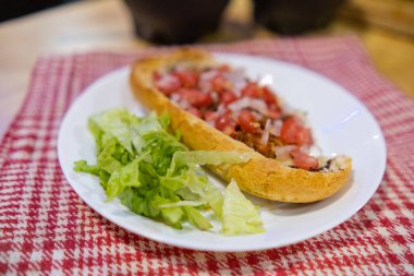 Beyaz ve kırmızı kareli peçetenin üzerindeki bir tabakta Meksika yumuşağı ve marul.