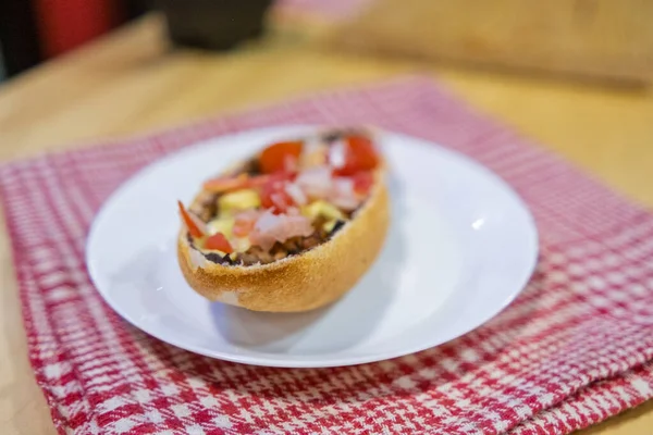 Tradiční mexický mollete na talíři nad bílým a červeným kostkovaným ubrouskem — Stock fotografie