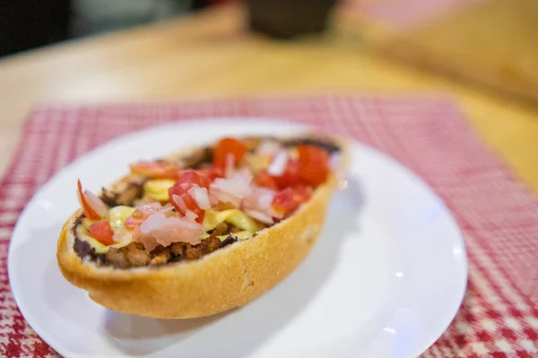 Tradiční mexický mollete na talíři nad bílým a červeným kostkovaným ubrouskem — Stock fotografie