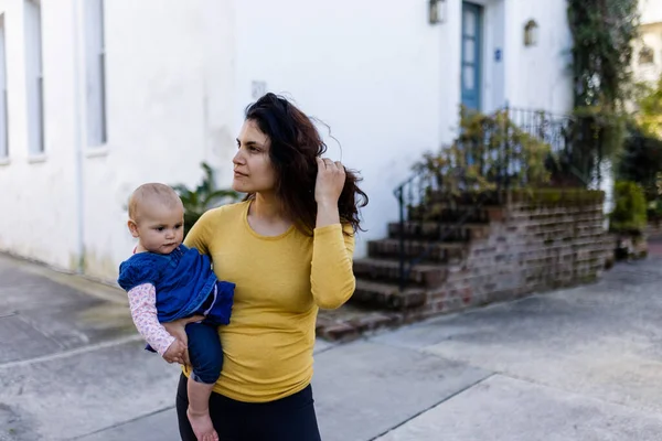 Bela mãe feliz segurando seu bebê bonito no bairro tranquilo — Fotografia de Stock