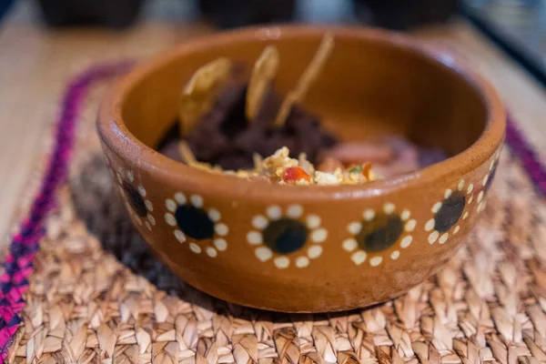 Vejce v mexickém stylu, slanina a smažené fazole s tortilla chipsy v hliněné misce — Stock fotografie