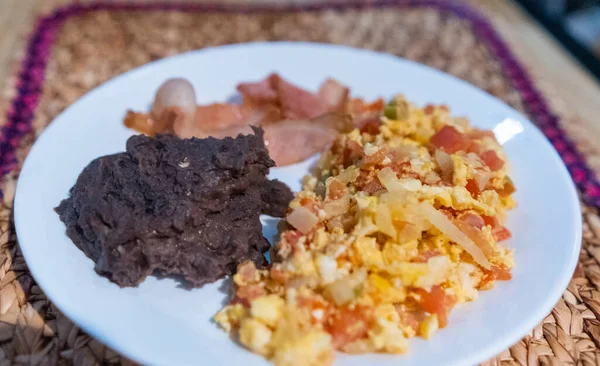 Яйця мексиканського стилю, бекон і смажені боби на білій тарілці — стокове фото