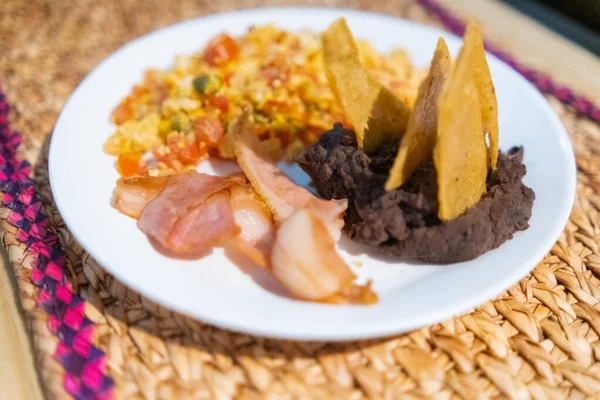 Mexická vejce, slanina a smažené fazole s tortilla chipsy na bílém talíři — Stock fotografie