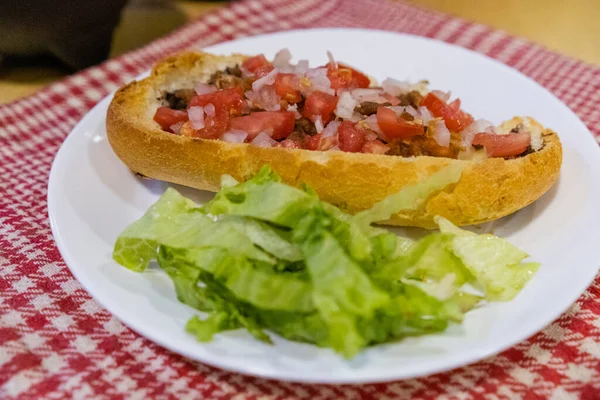 Mollete mexicano y lechuga en un plato sobre una servilleta a cuadros blanca y roja — Foto de Stock