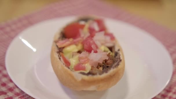 Παραδοσιακά Μεξικού mollete σε ένα πιάτο πάνω από λευκό και κόκκινο καρό χαρτοπετσέτα — Αρχείο Βίντεο