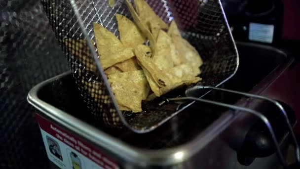 Hand placing deep fryer basket with tortilla chips above boiling oil — Stock Video