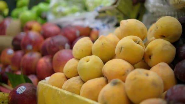 Primer plano del puesto de frutas de colores con montones de melocotones y ciruelas — Vídeos de Stock