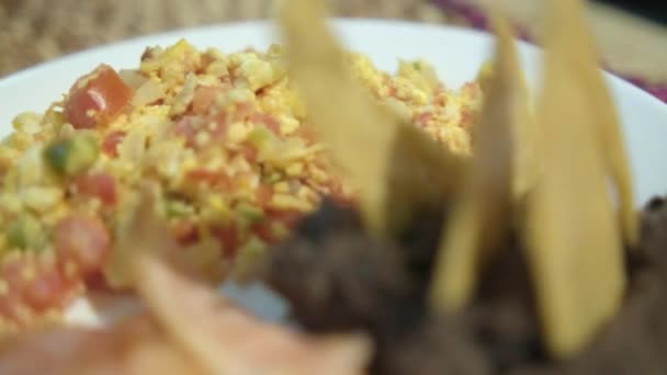 Ovos de estilo mexicano, bacon e feijão refrito com batatas fritas de tortilla no prato branco — Vídeo de Stock
