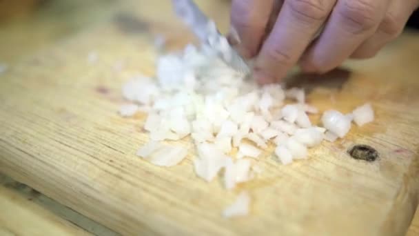 Manos cuidadosamente picando rodajas de cebolla sobre tabla de cortar de madera — Vídeos de Stock