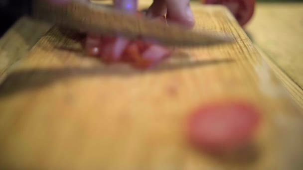 Manos cuidadosamente picando rodajas de tomate sobre tabla de cortar de madera — Vídeos de Stock