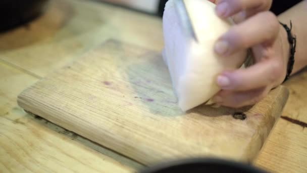 Manos rebanando cuidadosamente una cebolla sobre una tabla de cortar de madera — Vídeos de Stock