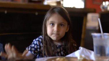 Restoran masasında oturmuş pizza yiyen sevimli küçük kız.