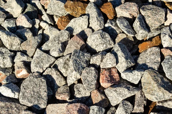 Background of natural grey granite crushed stone, macadam. Macro photo of texture of broken stone or rubble with place for text. Crushed rock. Construction Materials.