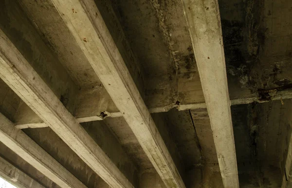 Reinforced Concrete Structure of Highway Overpass. View From Bottom Down. Cracking of concrete beams under the bridge. Under the overpass, the cement beams stretch wide and long to support the weight