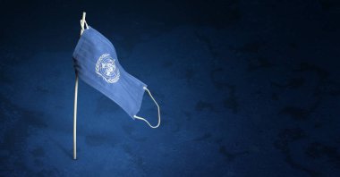 Koyu mavi arka planda Dünya Sağlık Örgütü maskesi. Dünya Sağlık Örgütü 'nün bayrağını direğe sallayarak. Virüs saldırısı bayrağı. Salgın koronavirüs COVID-19 'a karşı mücadele bayrağı kavramı. Boşluğu kopyala