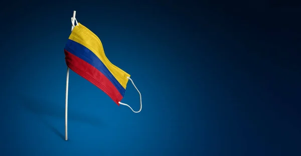 哥伦比亚面具深蓝色背景 挂在杆子上的医用面罩上的哥伦比亚飘扬的国旗 病毒攻击标志 防治流行病的横幅概念 Coronavirus Covid 复制空间 — 图库照片