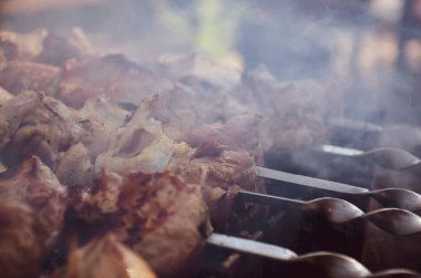 Shashlik ya da şiş kebap ızgaranın üstünde ateşte kızarmaya hazırlanıyor. Metal şiş üzerinde ızgara domuz eti. Şiş et parçaları ızgarada kızarıyor ve sigara içiyor.