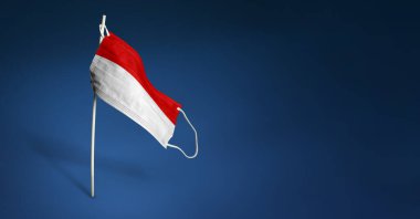 Koyu mavi arka planda Endonezya maskesi. Direğin üzerinde tıbbi maske ile Endonezya bayrağı sallıyordu. Virüs saldırısı bayrağı. Salgın koronavirüs COVID-19 'a karşı mücadele bayrağı kavramı. Boşluğu kopyala