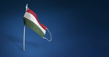 Koyu mavi arka planda Macar maskesi. Macaristan bayrağını direğin üzerinde tıbbi maskenin üzerine boyadı. Virüs saldırısı bayrağı. Salgın koronavirüs COVID-19 'a karşı mücadele bayrağı kavramı. Boşluğu kopyala