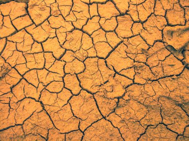 Toprak zeminde kuraklık ve ölüm kavramına sahip arkaplan veya grafik tasarımı için üst görünümde çatlaklar vardır..