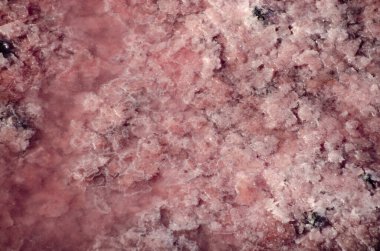 Tuz kristalli pembe tuzlu bir gölün yüzeyi. Kırmızı, tuzlu suda canlı bir bakteri. Tuzun doğal yoldan çıkarılması. Doğal doğal arkaplan