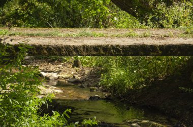 Dağdaki küçük sığ dereler ve kayalık araziler üzerindeki kırsal beton köprü. Terk edilmiş beton köprü derenin üzerinde..