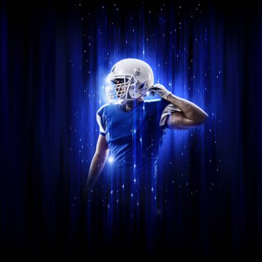 Süper kahraman pozu veren futbolcu siyah arka planda mavi ışıklarla mavi üniforma giyiyor..