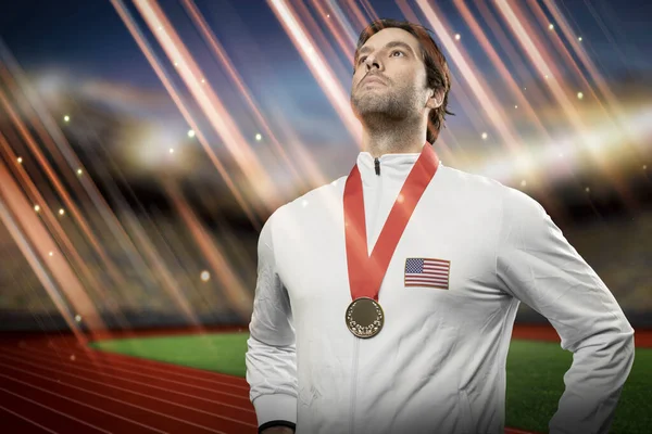 American male athlete smiling after winning a gold medal in a stadium. Sportsman with medal celebrating his victory.