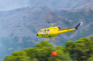 İtfaiye helikopteri Guadalest rezervuarından su için uçuyor, Alicante, İspanya.