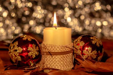 Noel süslemeli, arkaplanlı ve noel balolarıyla yanan mum..