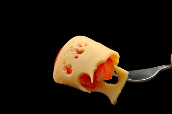 Cheese and tomato on a fork on black background — Stock Photo, Image