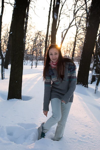 Attraktive junge Frau (Mädchen), die in warmer Kleidung mit Schnee spielt und im Park lächelt — Stockfoto