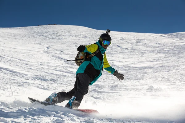 男子滑雪板滑雪上新鲜的白雪上的滑雪坡，在阳光明媚的冬日 图库图片