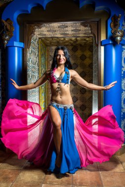 Muhteşem kostüm pembe ve mavi elbiseli güzel dansöz genç kadın. Mükemmel bir şekil ve vücut plastik ile güzel esmer