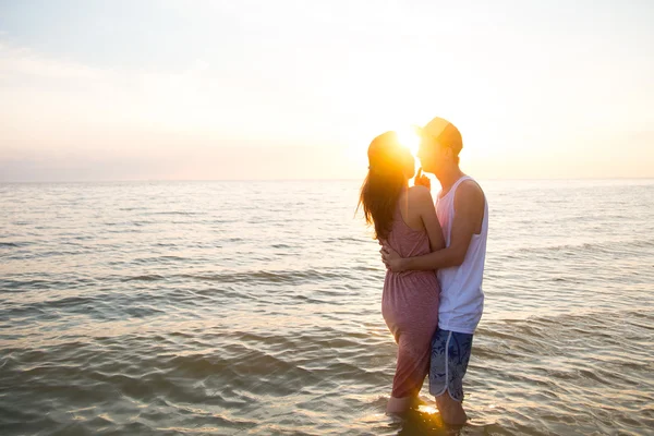 Jovem casal abraçando ao pôr do sol no mar — Fotografia de Stock