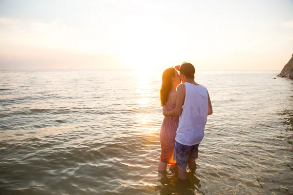 Jovem casal abraçando ao pôr do sol no mar — Fotografia de Stock