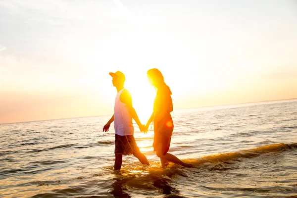 Jovem casal abraçando ao pôr do sol no mar — Fotografia de Stock