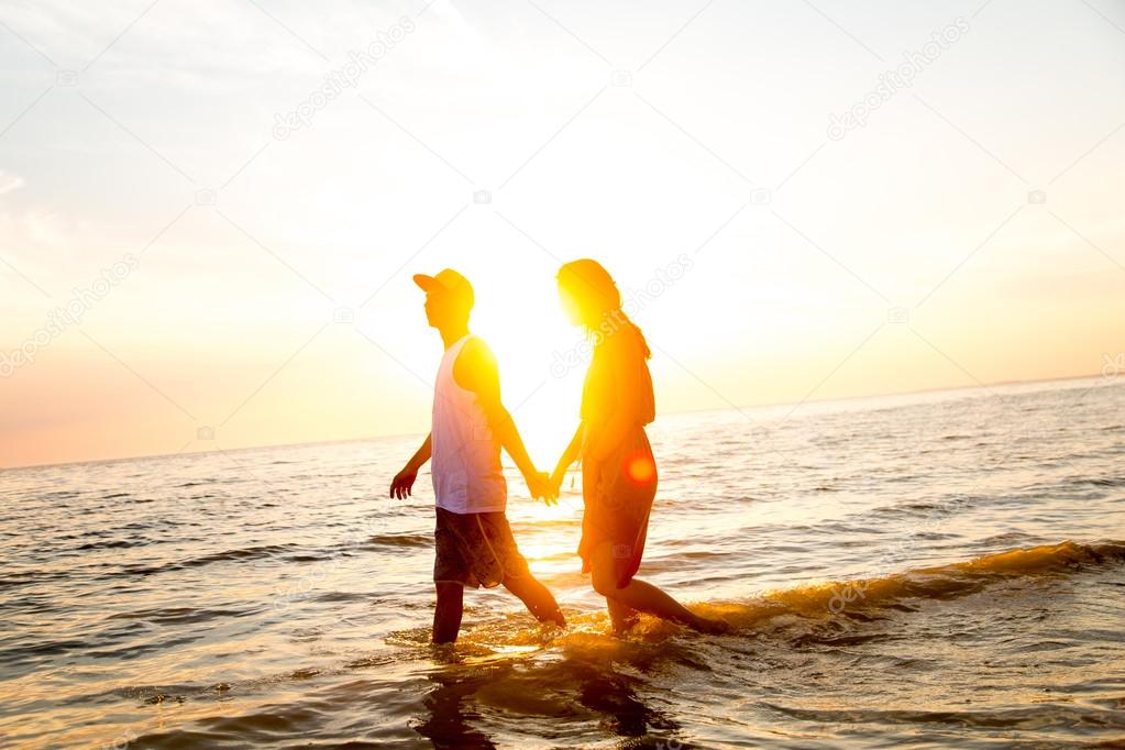 Young couple hugging at sunset in the sea