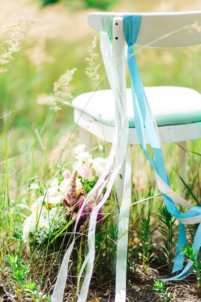 Bröllop dekoration stol. Trevligt arrangemang av är en stol dekorerad med färgade band på bakgrund av parken — Stockfoto