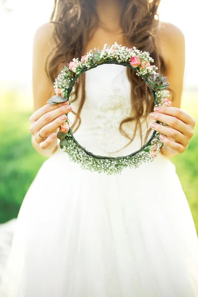 Noiva em vestido de noiva segurando uma coroa de luzes nas mãos — Fotografia de Stock