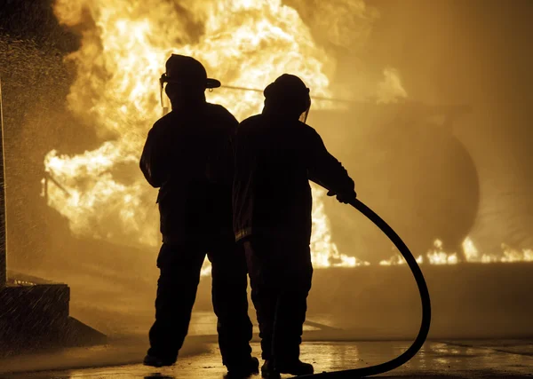 Two firefighters standing in front of a fire — Stock Photo, Image