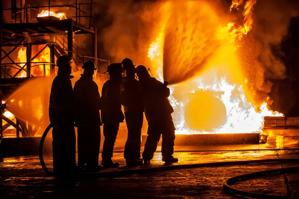 Группа пожарных, разбрызгивающих огонь водой — стоковое фото