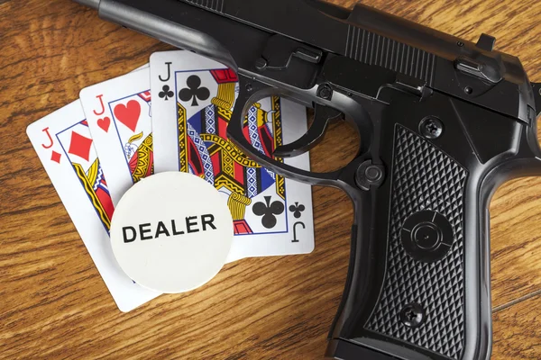 Illegales Glücksspielkonzept mit Handfeuerwaffe und Pokerhand und Dealer-Chip — Stockfoto